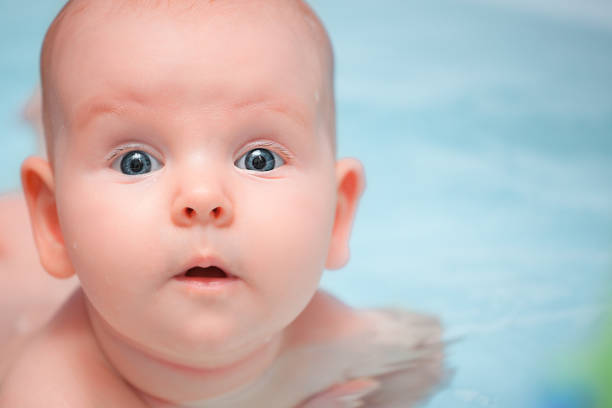 istock surprised baby swimming in the bath 1083498520