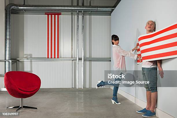 Young Woman Trapping Young Man Behind Striped Wallpaper Stock Photo - Download Image Now