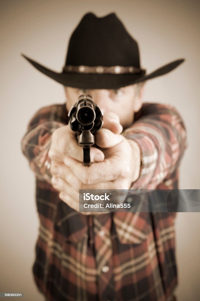 Cowboy che indica un'arma alla telecamera - Foto stock royalty-free di A quadri