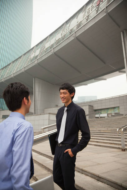 empresários chineses falando sobre degraus da cidade - staircase steps moving down student - fotografias e filmes do acervo