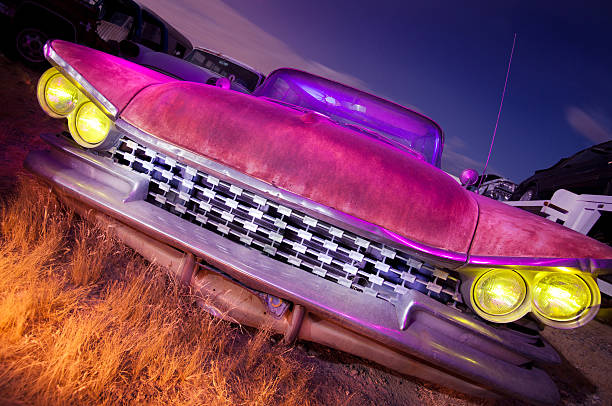 Old abandoned car at night.  Photographed using a light painting technique with 4 different colored gels.  Short star trails can be seen in the night time sky.
