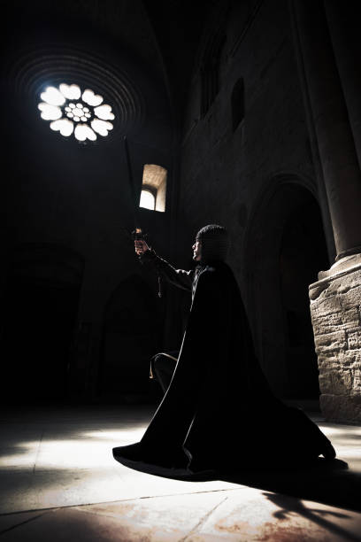 istock The Oath Kneeling Knight raising sword praying into cathedral light. 108350750