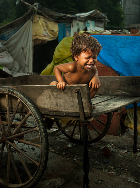 Poor, hungry child sitting on a cart and crying loudly  india poverty stock pictures, royalty-free photos & images