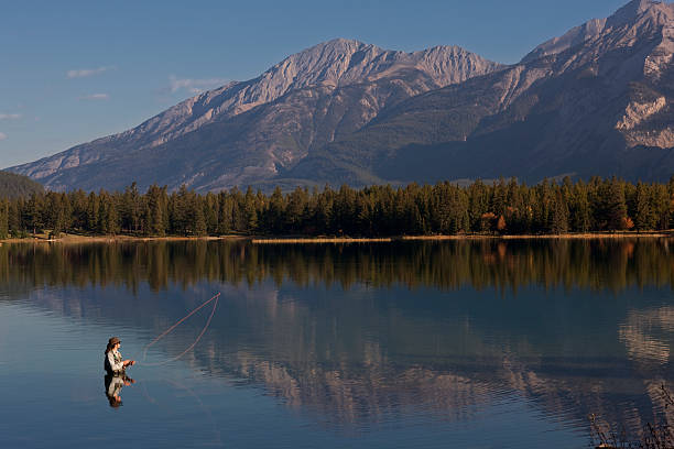 pêche à la mouche sur le lac edith dans les montagnes rocheuses, alberta, canada - wading vertical water sport recreational pursuit photos et images de collection