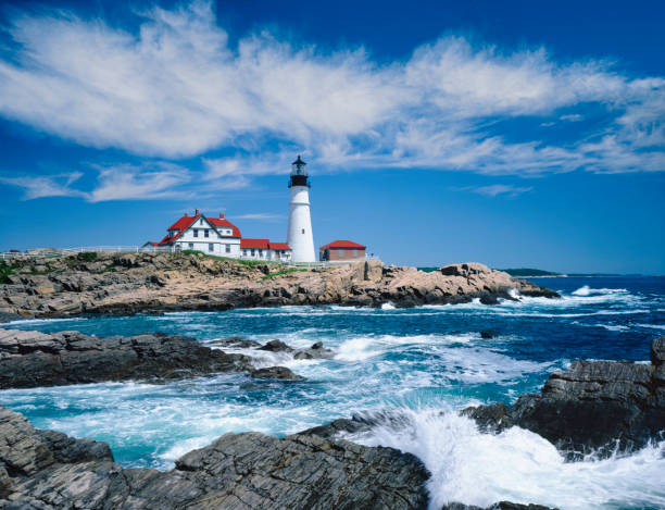 Waves Of The Alantic Ocean Crash Against The Rocky Cliffs Of Portland Head Light, Maine