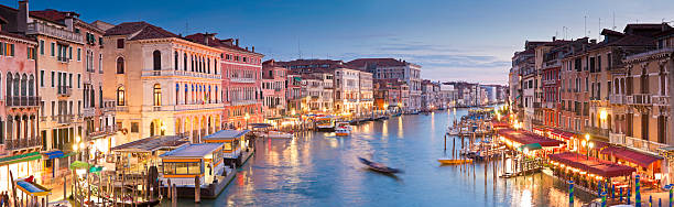 Grand Canal, Venice Pretty night time illuminations of colourful villas and gondolas overlooking the grand canal in Venice. Stitched panoramic image. grand canal venice stock pictures, royalty-free photos & images