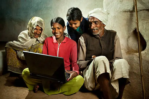 Photo of Happy village girl using laptop with mother, brother and grandfa