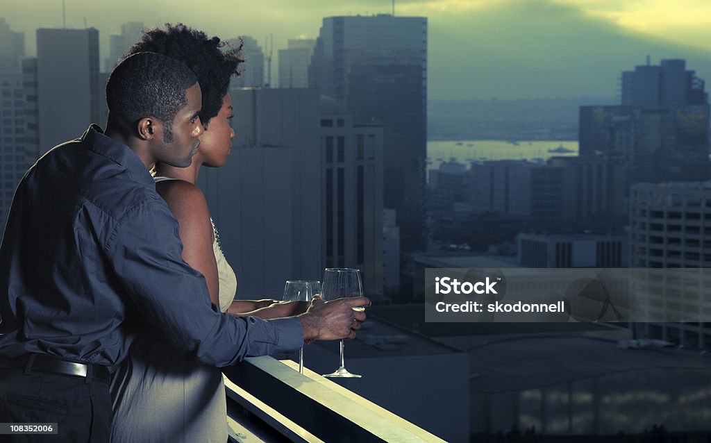 African American Couple in the City This is a photograph of a young African American couple enjoying wine on a balcony in downtown San Diego. This is a cross processed image creating a surreal sky. Couple - Relationship Stock Photo