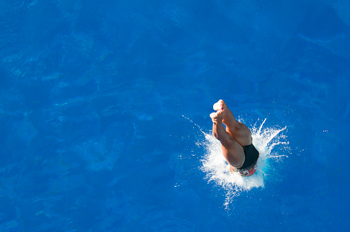 Professional lady diver breaks calm water surface. Convenient copy space