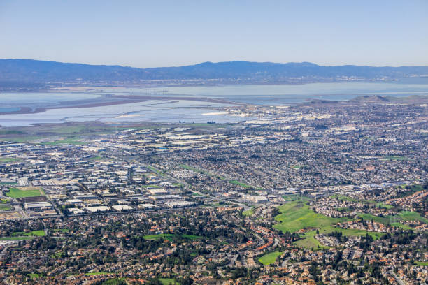 aerial view of fremont and newark on the shoreline of east san francisco bay area; dumbarton bridge in the background; silicon valley, california - bay san francisco county residential district aerial view imagens e fotografias de stock