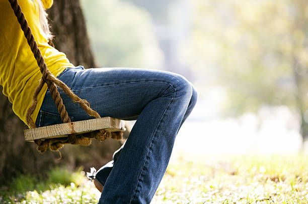 Feet swinging on wooden swing in front of a sustainable wooden house. Winter vacations.