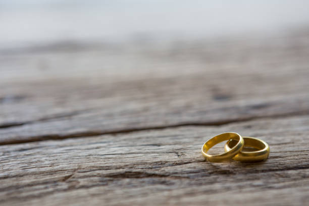istock Two gold rings on wooden background 1083528172