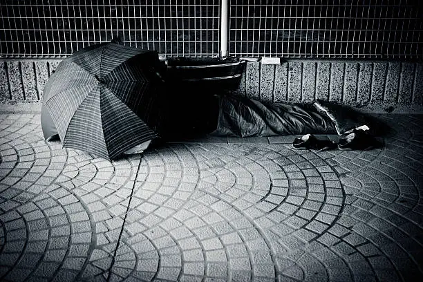 Photo of Homeless Man sleeping under umbrella