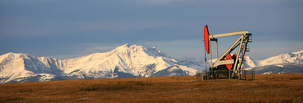 Pumpjack Panorama with Canadian Rockies in Distance  oil pump oil industry alberta equipment stock pictures, royalty-free photos & images