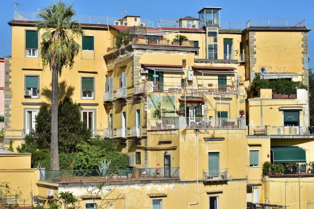 Multi story yellow Mediterranean house with terraces and flat roof on sea coast in Naples in Italy.