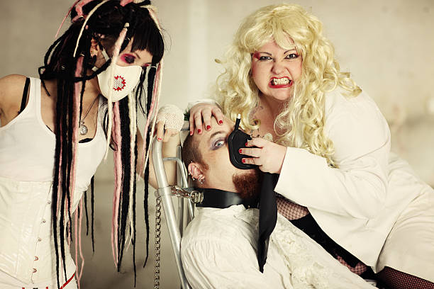 Oxygen therapy Patient is chained and gassed by Aggressive blond doctor and Psychopath nurse. Tied Up Bondage Women Fetish Wear stock pictures, royalty-free photos & images