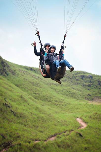 Soaring - Young couple doing tandem paragliding Real people, actual young couple doing tandem paragliding. Slight motion blur due to relative speed. paraglider stock pictures, royalty-free photos & images
