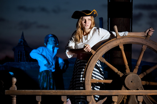 Two pirates on ship at night. Focus on woman