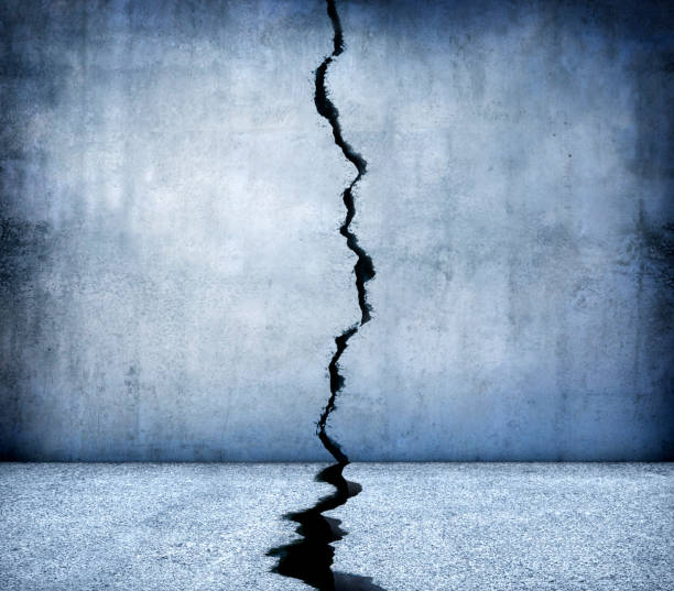 Crack Running Through Concrete Walls And Floor A large crack runs through the middle of a concrete floor and wall. separation stock pictures, royalty-free photos & images