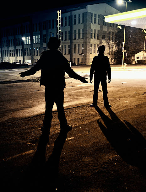 dangerous streets two dark figures face off on dark alley. gang stock pictures, royalty-free photos & images