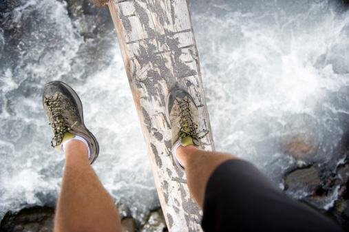 A man hiking on a log above a river 