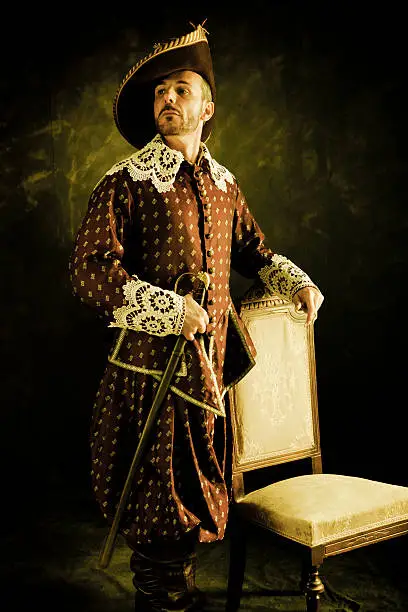 Man with  a period costume and a sword posing.