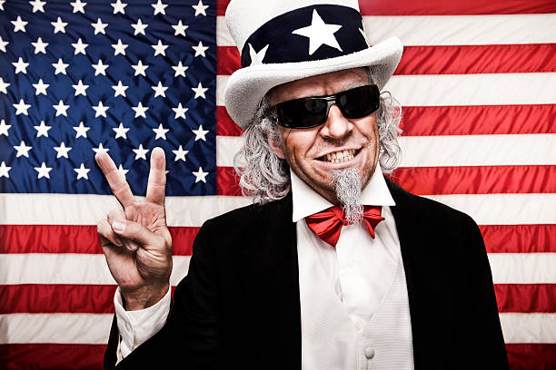 Uncle Sam with Sunglasses and Peace Sign A stock photo of Uncle Sam wearing dark sunglasses and making a peace hand gesture against a USA flag background. i want you stock pictures, royalty-free photos & images