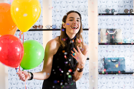 Attractive brunette woman holding balloon stars against grey studio wall banner background, holiday party celebration concept