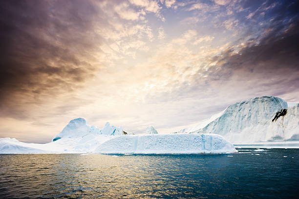 Sun rising over huge Icebergs in polar arctic icefjord at the west greenland coast. Ilulissat Icefjord, Greenland, North West Coast.