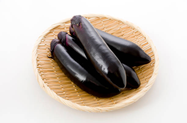 istock Raw black eggplant on bamboo sieve on white background 1083571200