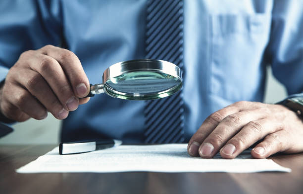 istock Businessman with magnifying glass reading document. 1083571316