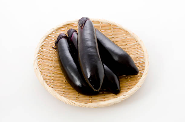 istock Raw black eggplant on bamboo sieve on white background 1083571408