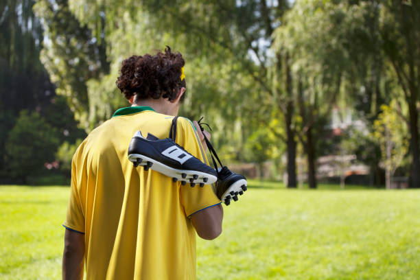 Chinese soccer player carrying cleats in park