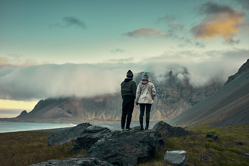 Couple on an Icelandic beach. Mountain range in background