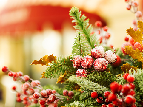 Christmas and New Year background with fir tree wreath and berries. Shiny golden decorations and light bulb bokeh.