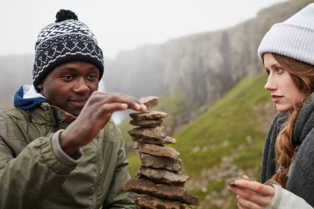 Multi ethnic couple building tower of rocks