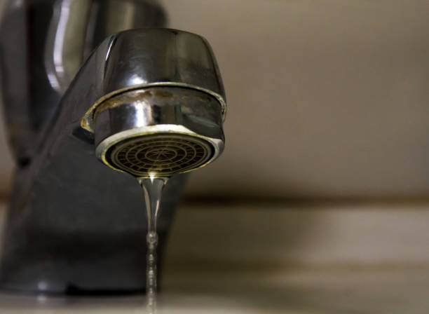 istock Leaking water drops from old rust and stained faucet 1083590966