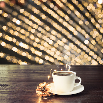 Cup of black coffee on wooden board in cafe. Blurred gold garland as background. Christmas Time. Image for display your products.
