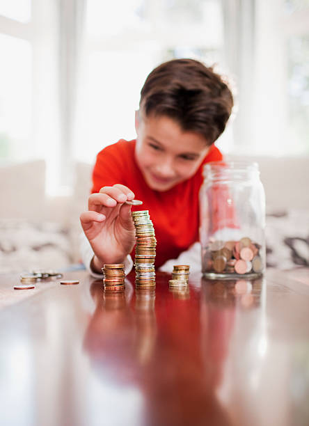 мальчик складывать в стопку монет - currency savings coin counting стоковые фото и изображения