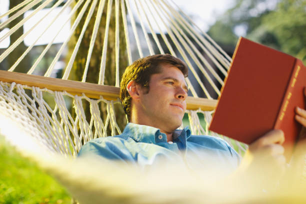 남자 알을 해먹에 누워 있는 독서모드 예약 - men reading outdoors book 뉴스 사진 이미지