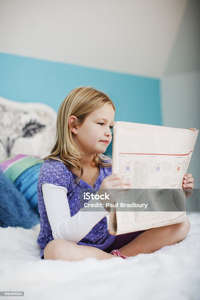 Fille assise sur le lit, lisant le journal - Photo de Journal libre de droits