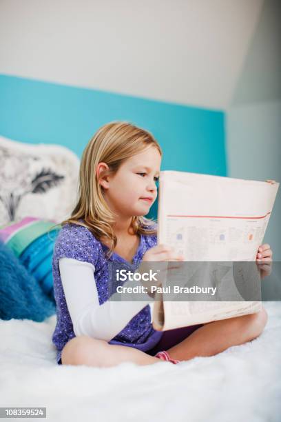 Photo libre de droit de Fille Assise Sur Le Lit Lisant Le Journal banque d'images et plus d'images libres de droit de Journal - Journal, Petites filles, 6-7 ans