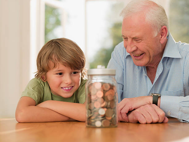 dziadek i wnuczek patrząc na słój jest pełny monet - jar penny coin currency zdjęcia i obrazy z banku zdjęć