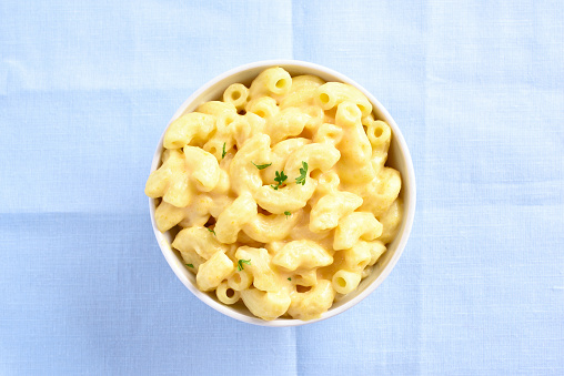 Macaroni and cheese with herbs in white bowl. Top view, flat lay