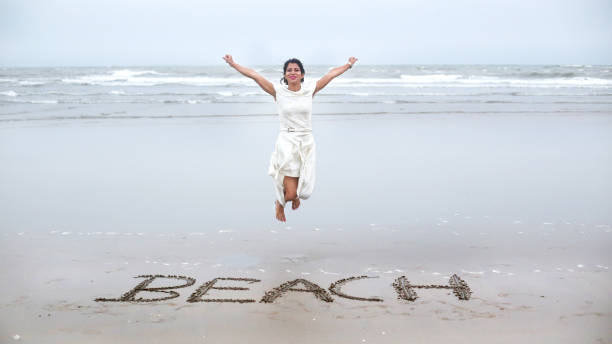istock Cheerful young woman jumping on tropical sandy beach 1083606120
