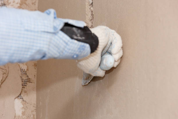 Hand with a spatula in the process of leveling the raw plaster. Hand with a spatula in the process of leveling the raw plaster. stucco repair stock pictures, royalty-free photos & images