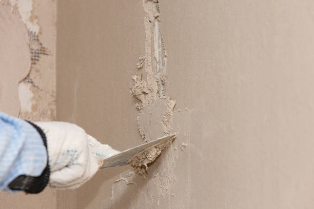 Hand with a spatula in the process of leveling the raw plaster. Hand with a spatula in the process of leveling the raw plaster. stucco stock pictures, royalty-free photos & images