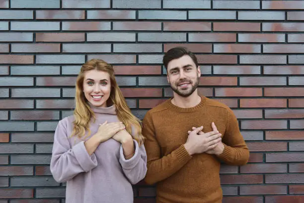 Photo of Portrait of cheerful young woman and man dressed sweaters, looking and smiling broadly at camera.