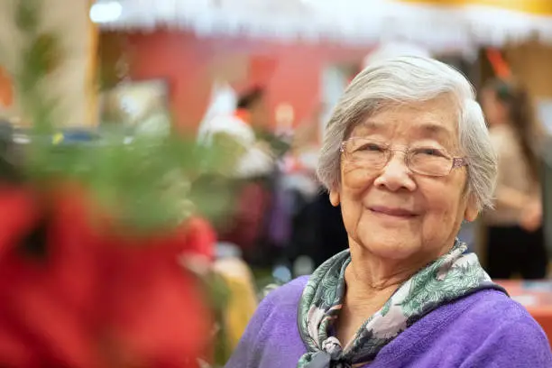 Chinese woman in her 90s enjoying Christmas party.  North Vancouver, British Columbia, Canada