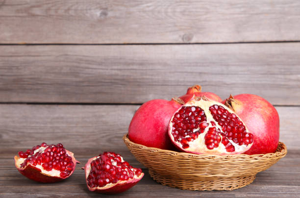istock Ripe pomegranates on basket on grey wooden background 1083614320
